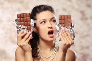 Portrait of beautiful young woman with chocolate on blurred background, close up